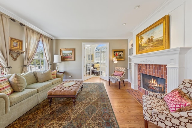 living room with a fireplace, baseboards, crown molding, and light wood-style floors