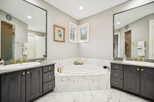 full bath with a sink, a garden tub, and two vanities