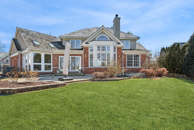 back of house with a patio, a yard, a chimney, entry steps, and brick siding