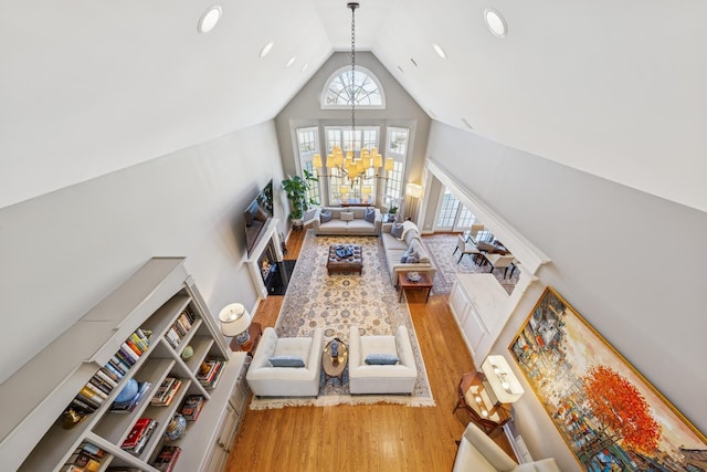 living area with a notable chandelier, wood finished floors, and high vaulted ceiling