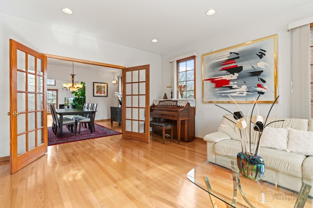 living room with french doors, a notable chandelier, recessed lighting, light wood-style floors, and baseboards