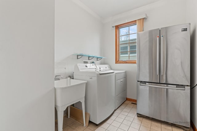 washroom with light tile patterned floors, laundry area, baseboards, washer and dryer, and ornamental molding