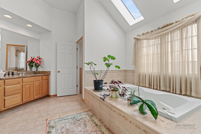 bathroom featuring a skylight, a whirlpool tub, tile patterned flooring, vanity, and high vaulted ceiling