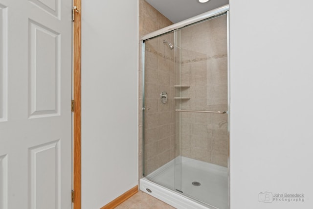 full bathroom featuring a stall shower, tile patterned flooring, and baseboards