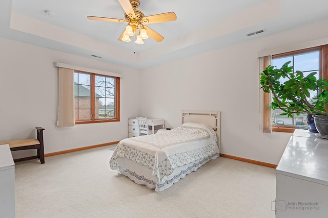 bedroom featuring light carpet, baseboards, visible vents, and a raised ceiling