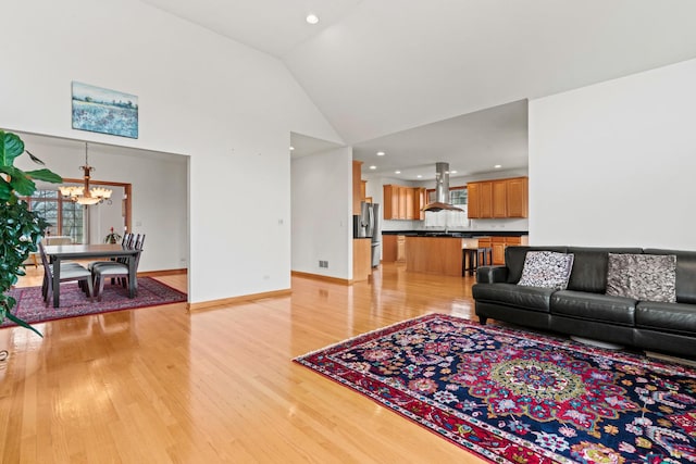 living area with high vaulted ceiling, recessed lighting, light wood-style flooring, a chandelier, and baseboards