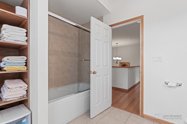 full bath with baseboards, a chandelier, combined bath / shower with glass door, and tile patterned floors