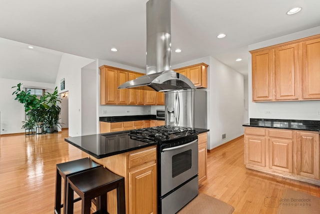 kitchen with appliances with stainless steel finishes, light wood-type flooring, dark countertops, and island range hood