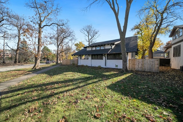 exterior space featuring a shingled roof, fence, and a yard