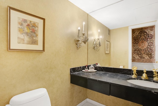 bathroom with visible vents, double vanity, a sink, and toilet