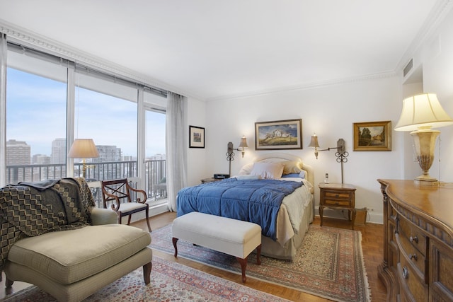 bedroom featuring a city view, visible vents, baseboards, access to outside, and crown molding