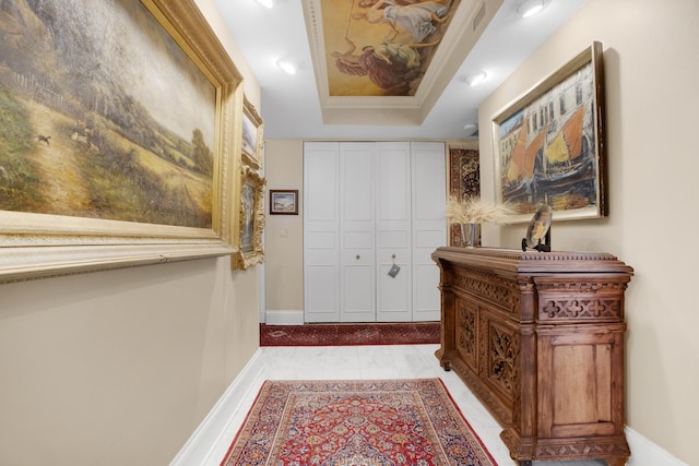 foyer featuring a tray ceiling and baseboards