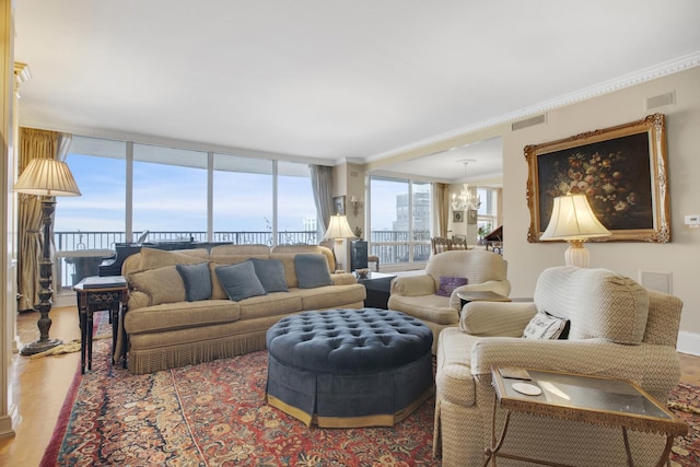 living room featuring a chandelier, visible vents, ornamental molding, and wood finished floors