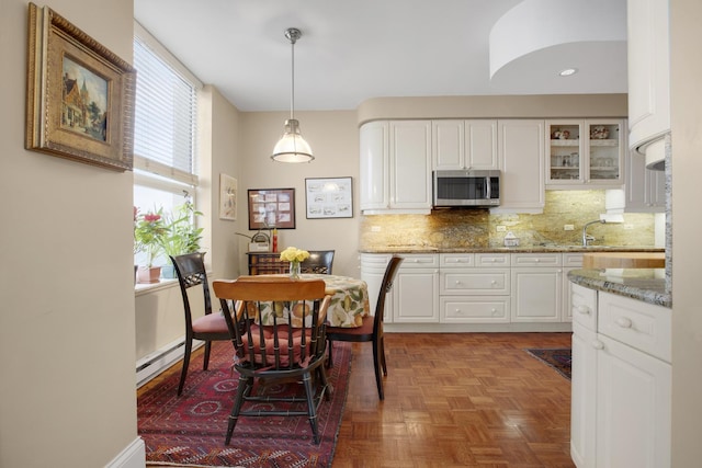 kitchen with glass insert cabinets, white cabinets, stainless steel microwave, and a baseboard heating unit