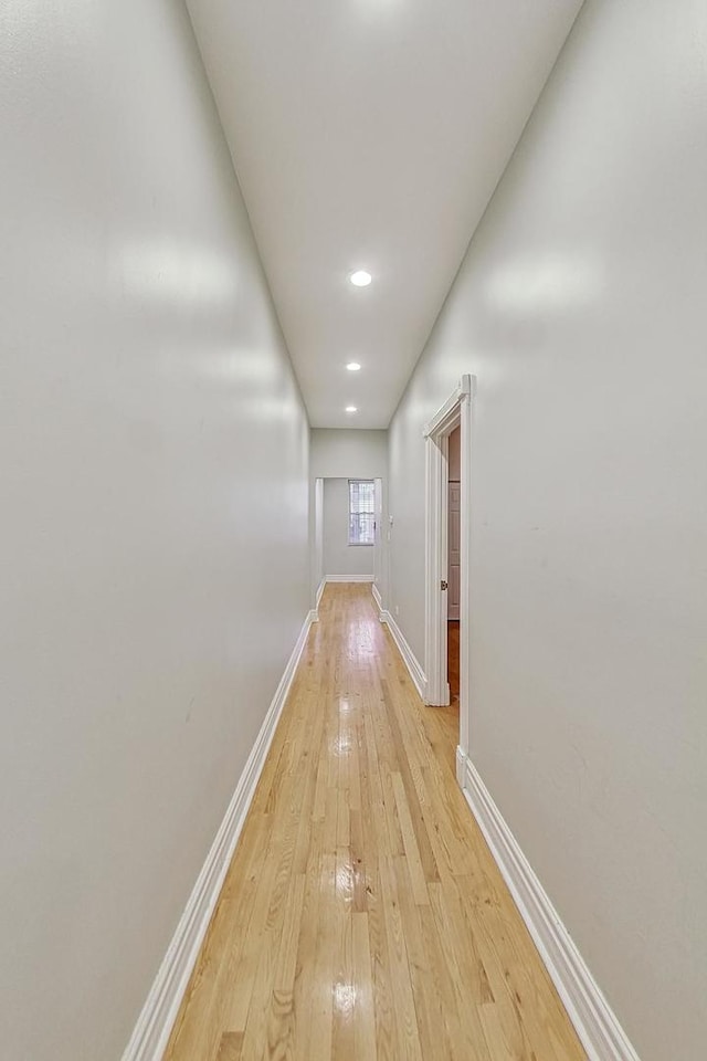 corridor with light wood-style flooring and baseboards