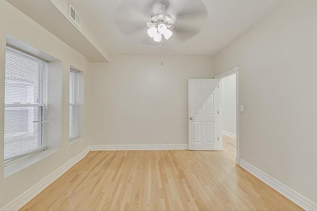 unfurnished room featuring light wood finished floors, visible vents, baseboards, and a ceiling fan