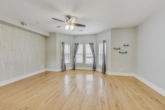 empty room with ceiling fan, baseboards, visible vents, and light wood-style floors