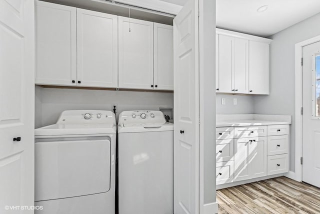 washroom featuring cabinet space, washing machine and dryer, and light wood finished floors