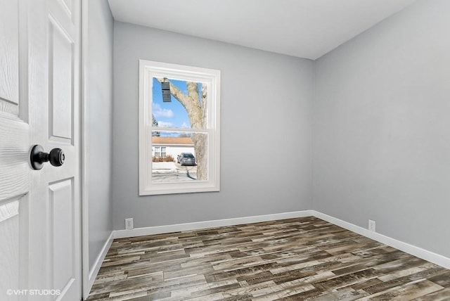 unfurnished room featuring baseboards and dark wood-type flooring