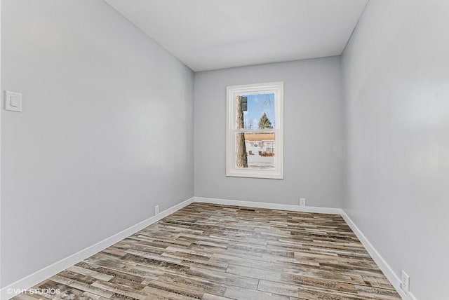 spare room with baseboards and wood finished floors