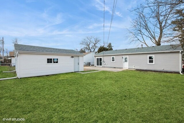 rear view of property featuring an outbuilding, a lawn, and a patio