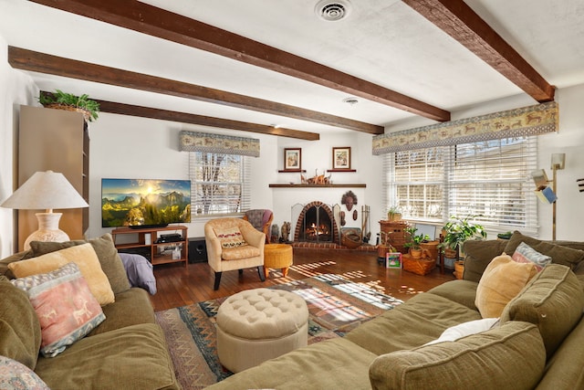 living room featuring a brick fireplace, wood-type flooring, visible vents, and beam ceiling