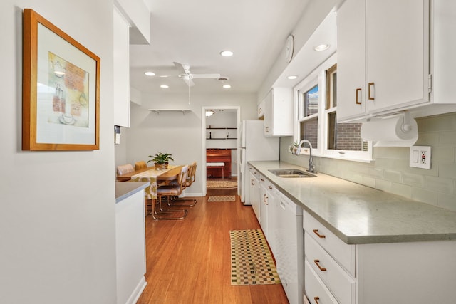 kitchen featuring tasteful backsplash, white cabinetry, a sink, light wood-type flooring, and white appliances