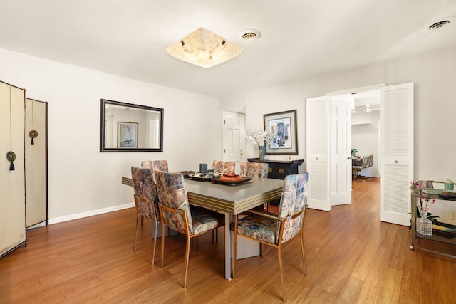 dining room featuring light wood-style flooring, visible vents, and baseboards