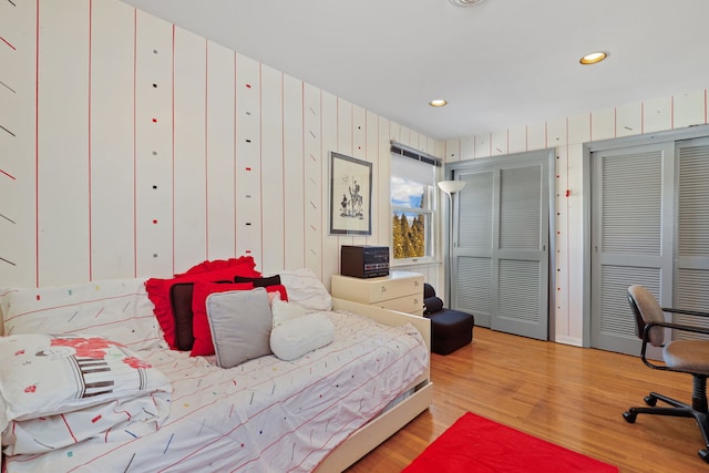 bedroom featuring recessed lighting, wood finished floors, and multiple closets