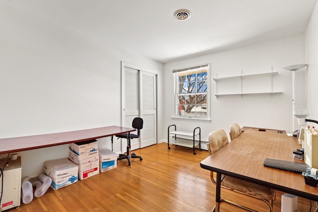 home office featuring a baseboard radiator, visible vents, and wood finished floors