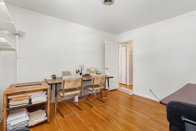 office featuring light wood finished floors, visible vents, and baseboards