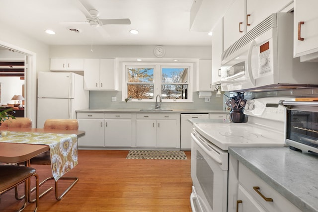 kitchen featuring white appliances, visible vents, white cabinets, and a sink