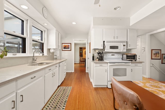 kitchen with light countertops, white appliances, a sink, and white cabinets