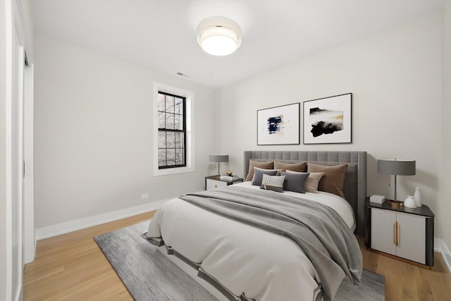 bedroom featuring light wood-style floors, visible vents, and baseboards