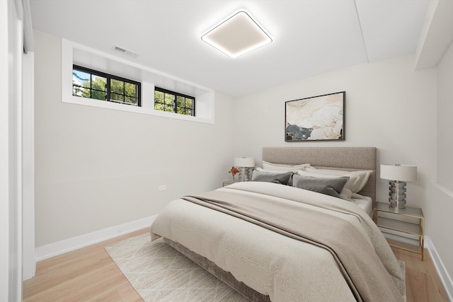 bedroom featuring visible vents, light wood-style flooring, and baseboards