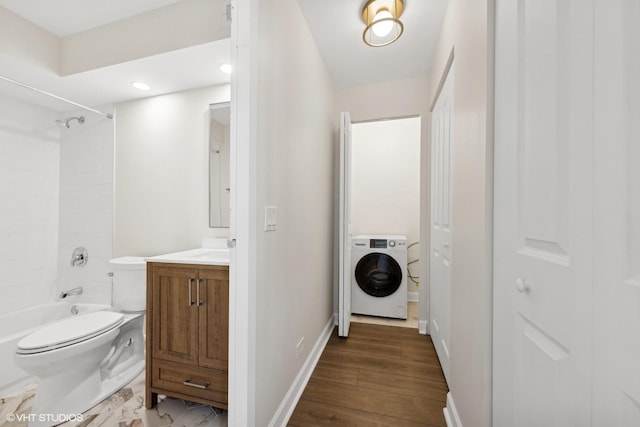 full bathroom featuring toilet, vanity, baseboards,  shower combination, and washer / dryer