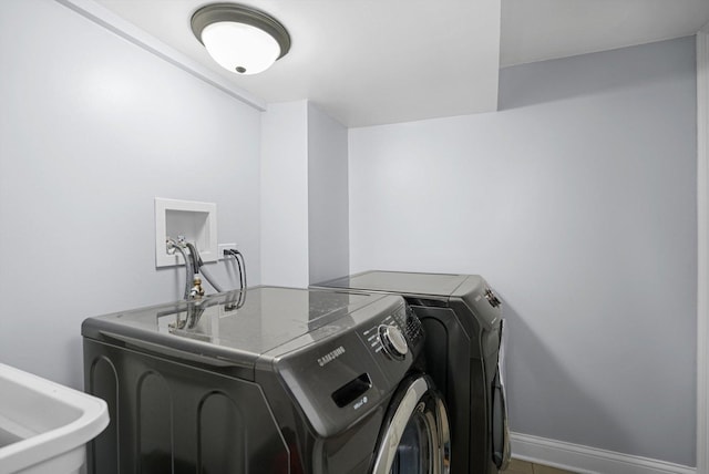 laundry area with a sink, laundry area, baseboards, and washer and dryer