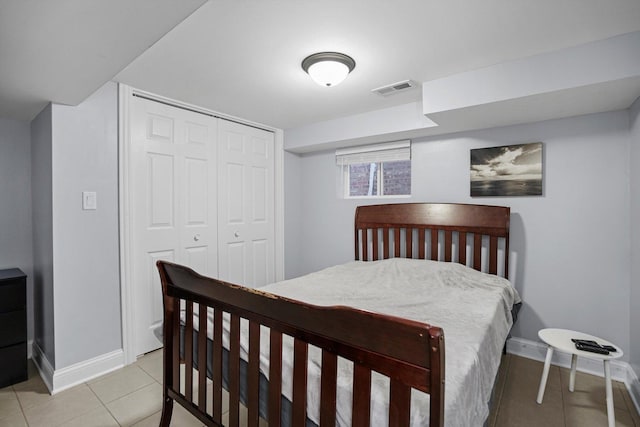 bedroom with light tile patterned floors, a closet, visible vents, and baseboards