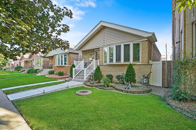 view of front of property featuring a fire pit, brick siding, a front lawn, and fence