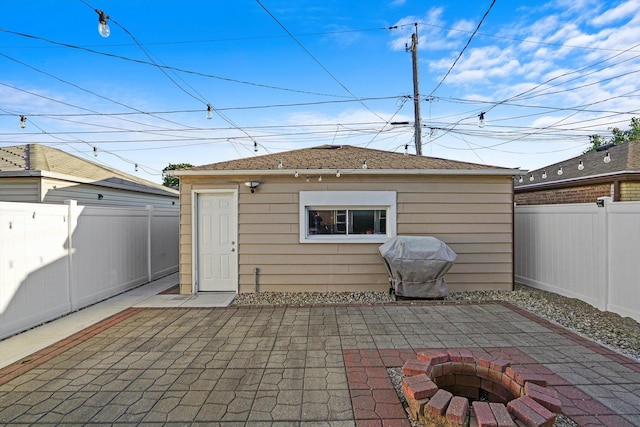 view of patio / terrace featuring a fenced backyard, a fire pit, grilling area, and an outdoor structure