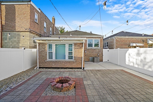 rear view of house featuring an outdoor fire pit, a fenced backyard, central AC, brick siding, and a patio area