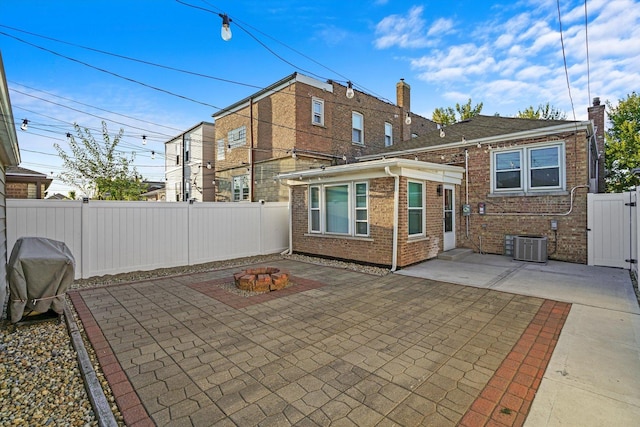 back of house featuring an outdoor fire pit, brick siding, a patio, and a fenced backyard