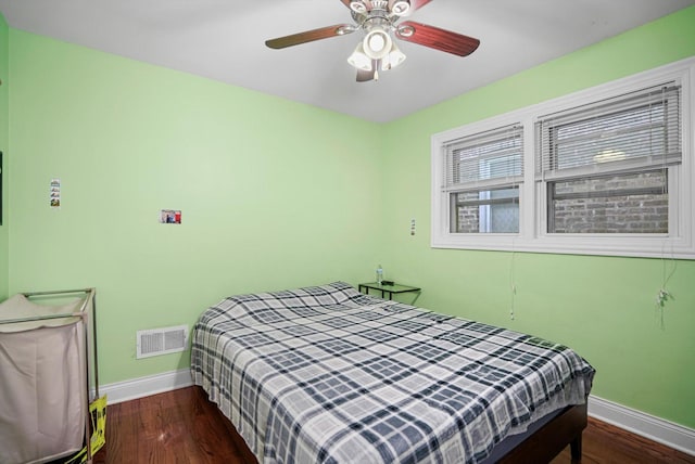 bedroom with dark wood-style floors, visible vents, and baseboards