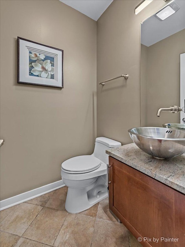 half bathroom with toilet, baseboards, and vanity