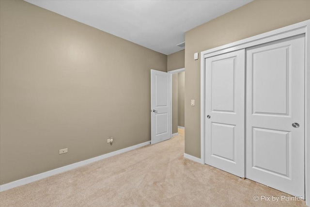 unfurnished bedroom featuring light carpet, a closet, and baseboards