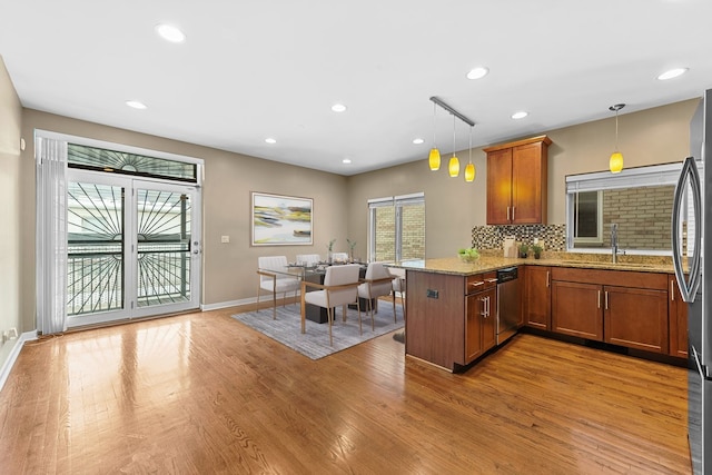 kitchen with stainless steel appliances, brown cabinets, hanging light fixtures, and a peninsula