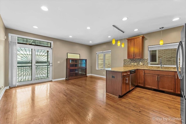 kitchen featuring a peninsula, stainless steel appliances, brown cabinets, and pendant lighting