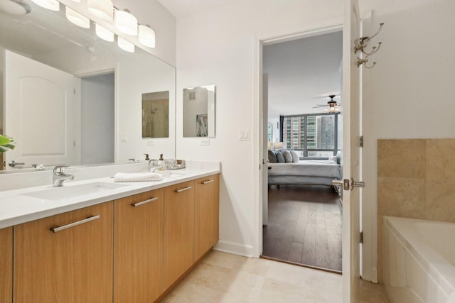 bathroom with a sink, a ceiling fan, a bath, double vanity, and ensuite bath