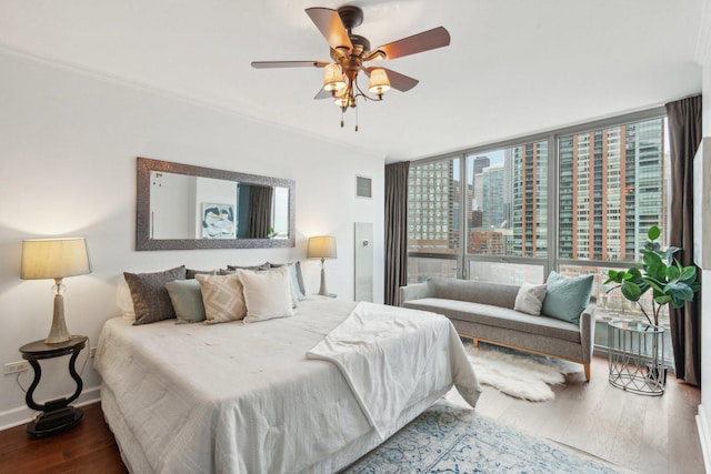 bedroom featuring baseboards, visible vents, wood finished floors, expansive windows, and a city view