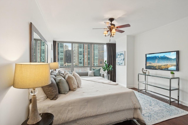 bedroom featuring ceiling fan, wood finished floors, baseboards, ornamental molding, and expansive windows